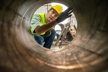 Worker inspecting steel pipe manufacturing facility industrial setting close-up view safety focus