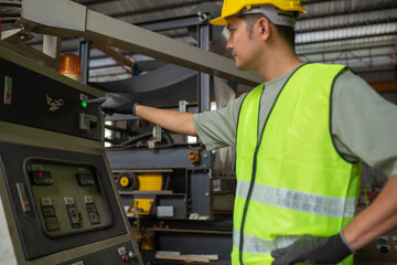 Industrial worker operating machinery factory floor action shot controlled environment side view safety awareness
