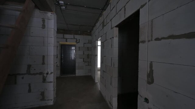 Unfinished room with concrete block walls and ceiling. Electrical wiring is visible. A doorway leads to another unfinished space.