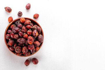 Bowl of dried rose hip berries on white background