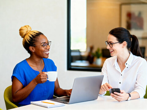 coworkers discussing project on mobile phone and laptop in modern workspace
