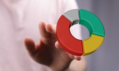 A hand holding a vibrant 3D pie chart, representing business, finance, and data visualization....