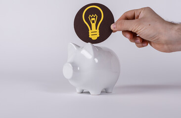 Conceptual shot of hand adding idea into piggy bank, showing concept of savings, investment and...