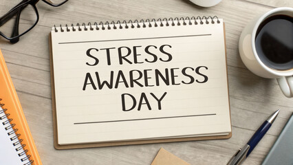 Stress awareness day message on notebook with coffee, glasses, pen, and smartphone on wooden desk, calm mood and soft light for wellness theme