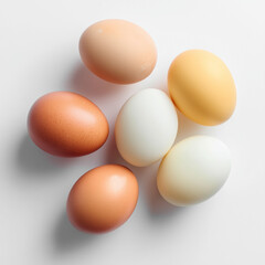 Assorted raw eggs in shades of brown and white placed on clean white background, captured in soft natural light.