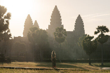 Woman traveling angkor wat admiring sunrise and historic temple