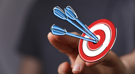 Close up of a hand touching a drawn bullseye with arrows, symbolizing goals, success and hitting...