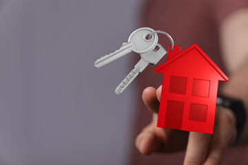 Concept of buying a new home with hand holding house key with red house model. Real estate, new...