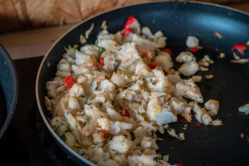 Cooked cauliflower mixed with chopped red pepper and herbs in a black non-stick frying pan. A simple, healthy stir-fry dish, lightly browned and ready to serve as a side or main course.