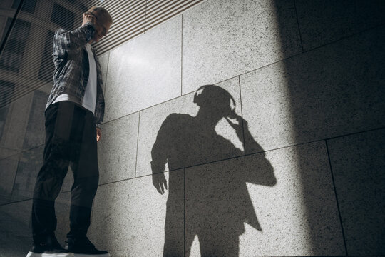 Young albino man listening to music against wall