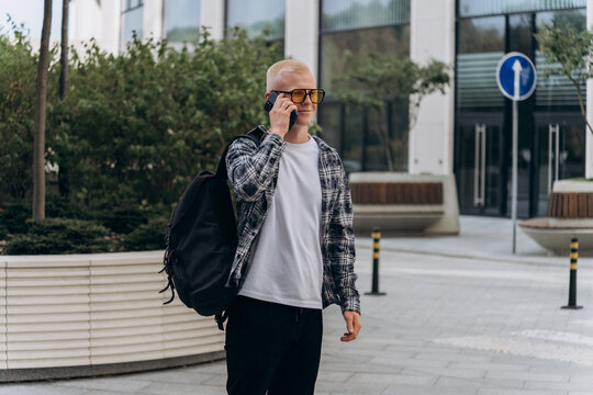 Young man using smartphone outside modern building - Powered by Adobe