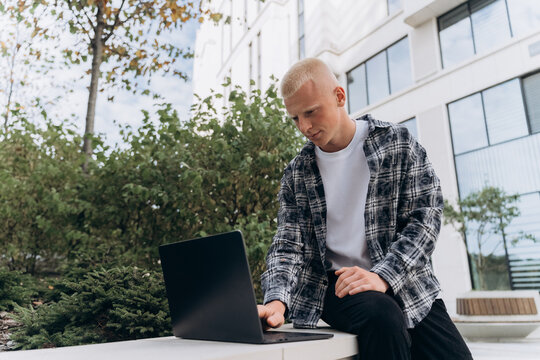 Young man with laptop in modern cityscape