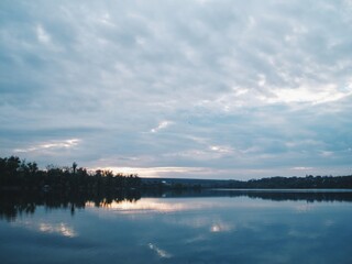 Fototapeta premium Wide reservoir at twilight with cloud breaks and quiet water 