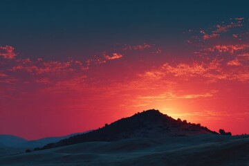 Obraz premium Scenic sunset over rolling hills casts vibrant red and orange hues across the sky near a distant mountain range landscape