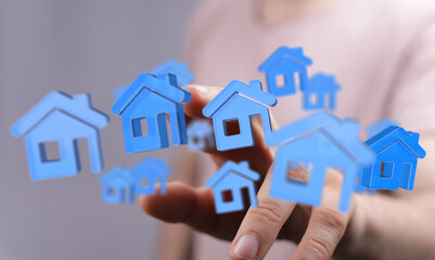 Person's hand with blue house icons floating, conceptualizing housing market, real estate investments, and home purchase. Innovative approach to