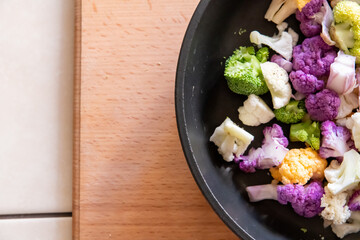 Colorful mixed vegetables ready for cooking in a black frying pan