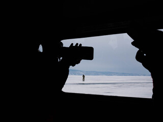 artist uses silhouette to depict solitary person on frozen coast during overcast weather conditions
