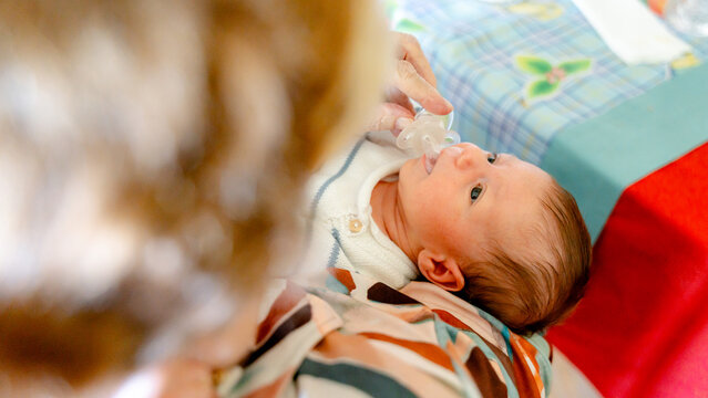 Newborn gazing up with a pacifier in hand