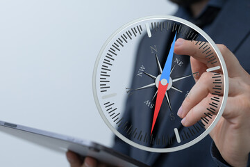 A close-up of a businessman holding a compass representing direction, strategy, and decision-making for business success.