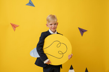 Schoolboy with bright idea symbol on yellow background