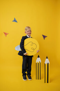Cheerful schoolboy holding a bright idea bulb