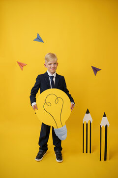 Portrait of a creative schoolboy holding paper bulb