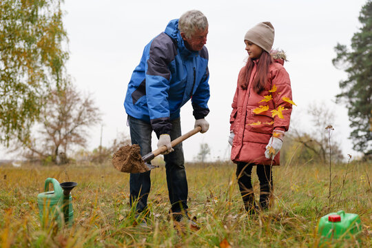 A grandfather teaches his granddaughter about planting as they work together in a field. The cool autumn air adds a refreshing feel to their time outdoors - Powered by Adobe