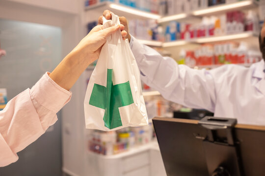 Pharmacist hands a bag to a customer at the pharmacy