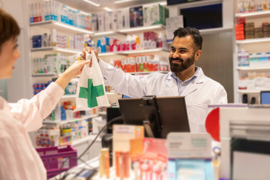 Pharmacist assisting customer in modern pharmacy