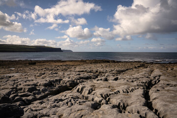 The striking rocks on the coast of Doolin in County Clare, Ireland, at the Burren, with the Cliffs of Moher in the background.