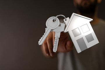 Hand holding keys and a house shape symbolizing real estate, buying, selling, and home ownership concepts. Perfect for illustrating mortgage, ne