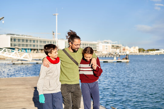 Father enjoying a sunny day at the waterfront with his children