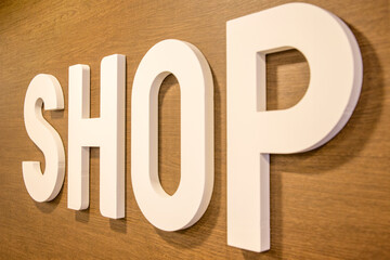 Closeup of the Shop sign in large white letters on a wooden wall.