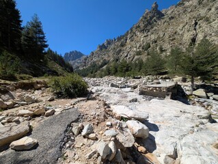 a destroyed bridge in the hiking area of the Restonica Valley with lots of debris in the sunshine