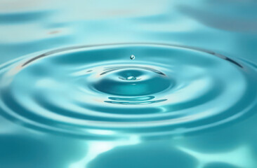 Water drop creating ripples on blue surface