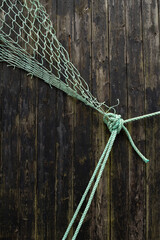 A green fishing net resting on dark wooden planks, evoking a rustic and nautical atmosphere.