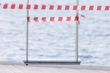 A wet swing after the rain, fenced off with white and red warning tape.