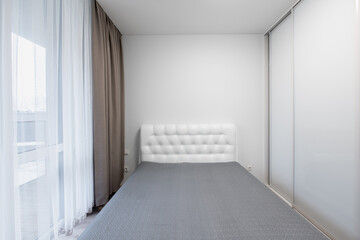 Minimalism Home Bedroom Interior. King Size Double Bed, Windows and Curtains. White Walls and Ceiling