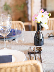 Restaurant table setting with cosmos flowers and cutlery