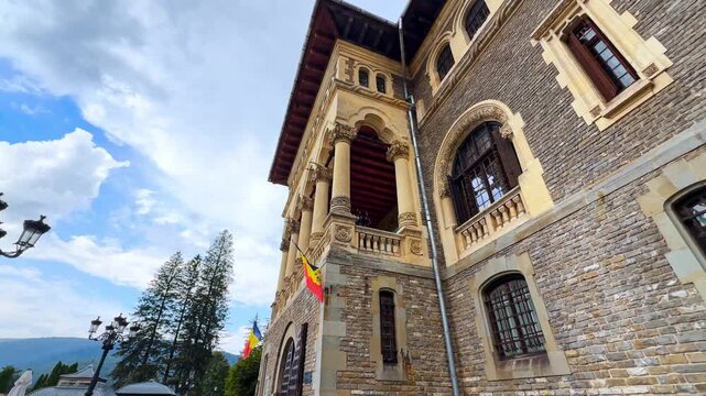 Exterior of a beautiful Cantacuzino Castle in Busteni, Romania. Low angle view at the fa&ccedil;ade with columns and flags.