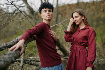 Young couple in matching burgundy outfits pose naturally outdoors, conveying genuine connection and...