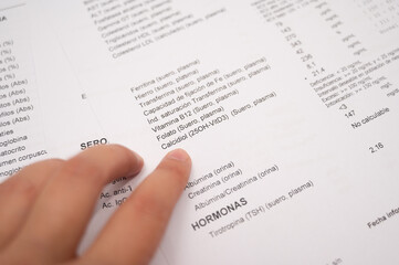 Obraz premium Finger pointing at blood test results, showing cholesterol levels on a Spanish medical report