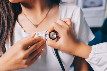 Doctor examining patient with stethoscope in hospital bed. Medical care and healthcare concept in a...