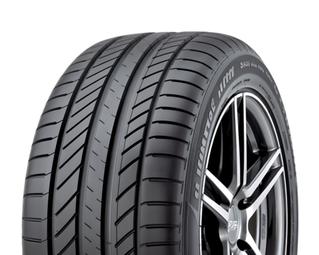 Close up of a new car tire with a silver alloy wheel against a black background