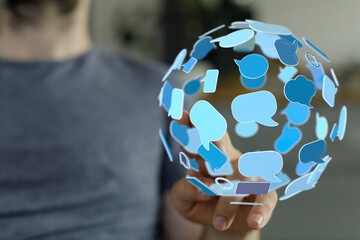 A person's hand touching a sphere of speech bubbles symbolizing global communication and social connection in a technological context.