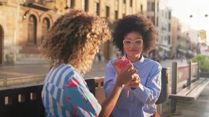 Friends sharing ice cream on a sunny downtown street