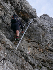 mountain climber ascending a ladder in the Herzogsteig via ferrata on Mt. Hochkoenig, Berchtesgaden alps, Austria