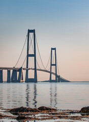 Obraz premium View of the Great Belt Suspension Bridge Reflected in Calm Sea Water at Sunset