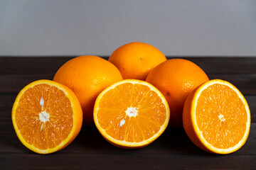 Fresh ripe oranges with slices on dark wooden table