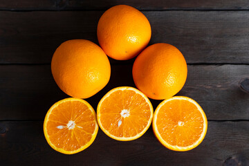 Fresh ripe oranges with slices on dark wooden table